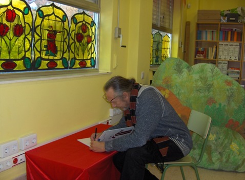 O escritor Ricardo Gómez firmando o libro de visitas da nosa biblioteca
