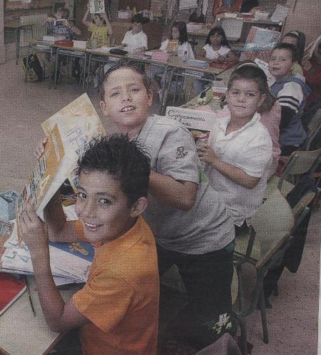 Nenos e nenas no primeiro día de cole ensinando o s libros novos